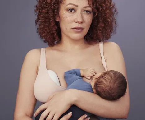 Mujer amamantando bebé con extractor de leche Elvie Pump en el otro seno